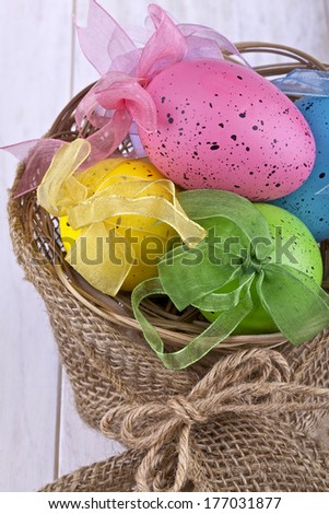 Easter decorative eggs in the basket on a light background,artificial