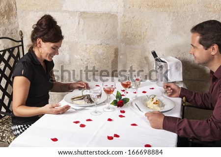 Love couple eating at the table, an old-fashioned restaurant, the tablecloth is decorated with rose blossoms