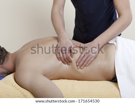 Massage therapy. a physiotherapist treats a patient. the back is massaged