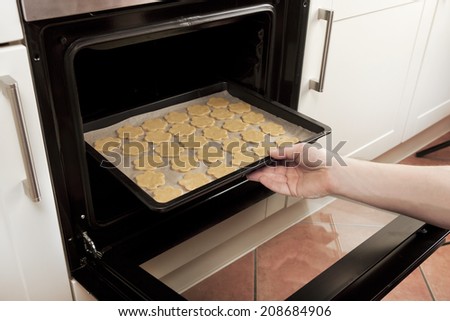 baking tray with cookies is pushed into the oven