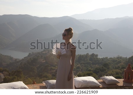 Woman in dress with fan on a terrace in the Spanish mountains