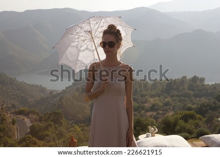Woman in dress with umbrella on a terrace in the Spanish mountains