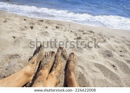 four feet of a couple on the beach, in the background the waves of the ocean