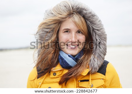 young woman with hat in winter on the beach, the hair will be gone with the wind
