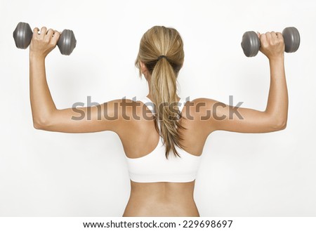 a woman in a white sports top trained their upper arms with dumbbells
