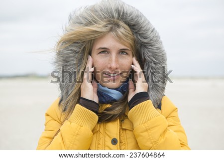 young woman with hat in winter on the beach, the hair will be gone with the wind
