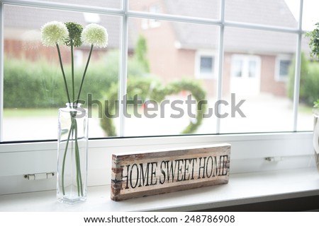 on a window sill in the house is a sign with the text home sweet home