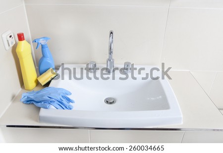 a dirty and calcified sink with cleaning gloves and cleaning products