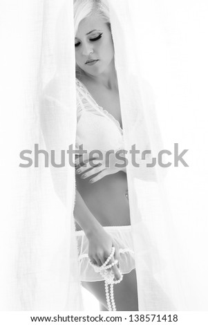 blonde woman standing behind the curtains