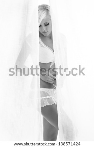 blonde woman standing behind the curtains