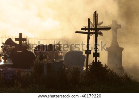 All Saints, cemetery at sunset with cross and silhouetted against sky,