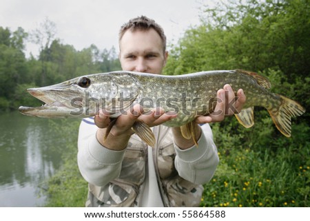 happy fisherman presents big pike, caught big fish