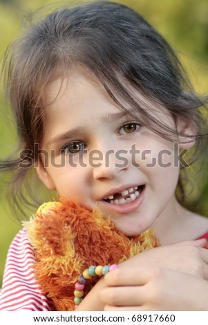 portrait young girl, smile and milk tooth loss, girl hugging teddy bear