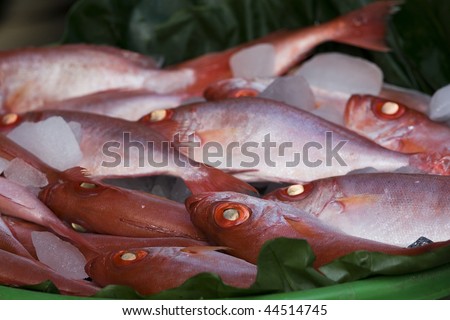 Red sea fish on a basket of leaves.  These attractive fish are for sale in a wet market.