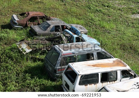 Old and unwanted cars and vans rot on some wasteland.  The cars will probably be scrapped.