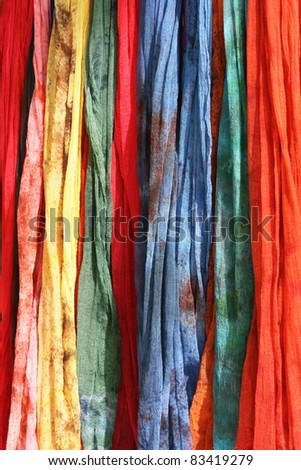 Colorful Scarves on sale at a market.  They come in blue, red, green, yellow and pink.