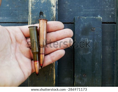two old cartridge in a man\'s hand on a wooden background