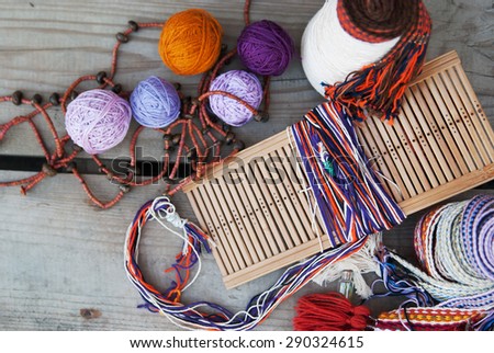 tools and thread for weaving on a wooden background top view