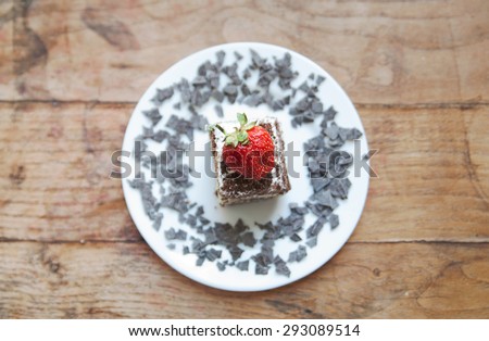 strawberry on the cake on a white plate decorated with chopped chocolate. view from above
