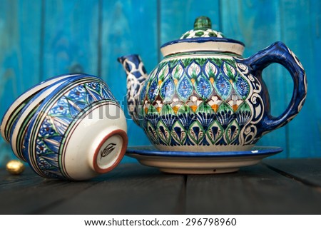 Ethnic Uzbek ceramic tableware  on the blue wooden background. ceramic teapot and cup