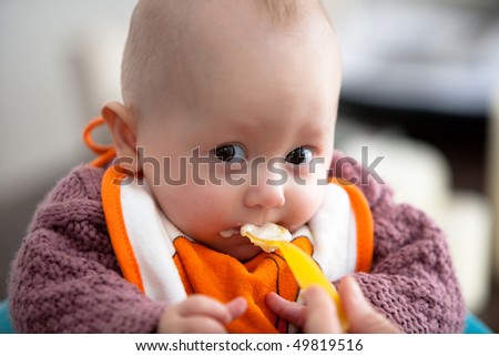 A baby girl eating one of her first meals.