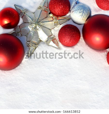 a collection of red, silver and gold Christmas decorations and bulbs are laying outside framing the freshly fallen snow for text, copyspace.