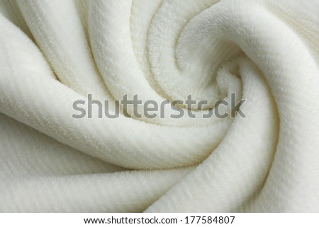 a soft white, plush micro fleece fabric blanket is swirled into a circular pattern background