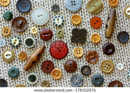 collection brown, tan, and natural colored wood vintage sewing buttons scattered on a tweed knitted fabric background