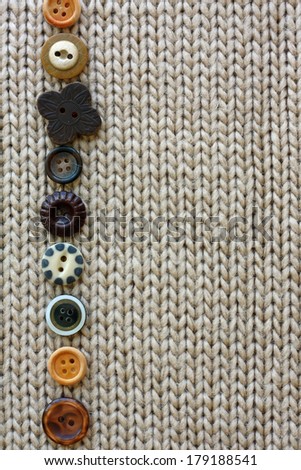 a row of natural colored vintage sewing buttons are lined up, framing tan tweed fabric background