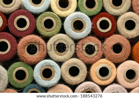 a collection of round, natural colored, vintage yarn spools organized as a background.