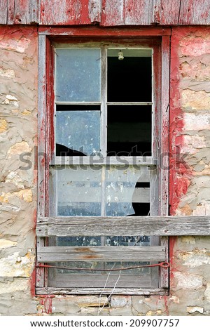 The glass is broken on an old window framed with weathered barn-wood on a vintage barn.