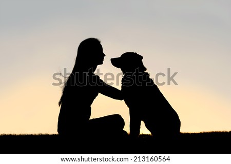 a special and serene moment as a girl is lovingly hugging and looking into the eyes of her German Shepherd Dog, silhouetted against the sunsetting sky