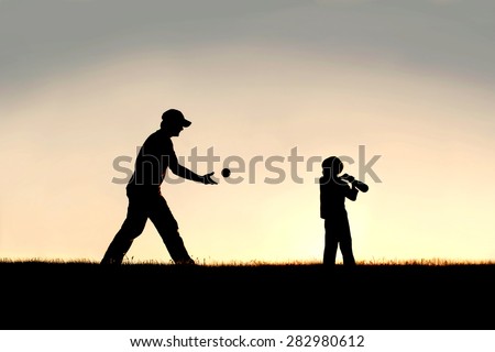 A silhouette of a young father and his little boy child playing baseball outside on a summer evening.