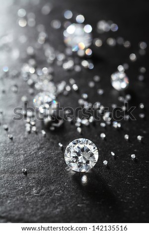 putting diamonds on the surface of the stone closeup. more diamonds out of focus in background