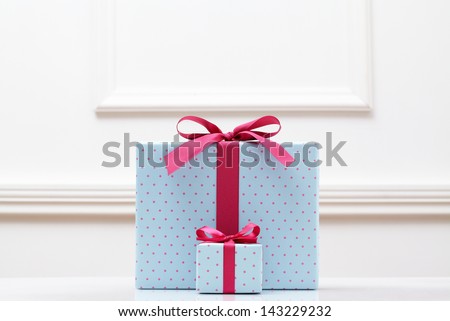blue gift box on white table. Different sizes of the same shape gift box. A small gift box with a big gift box.
