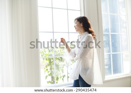 beautiful women looking out a window with a smile on their face in a bright room