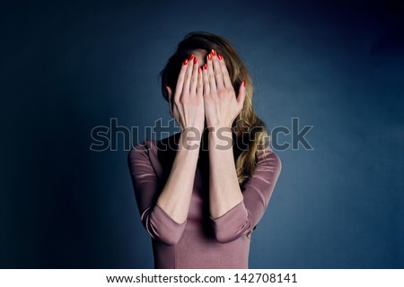 beautiful young girl in a brown dress, her hands covering her eyes