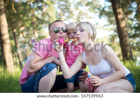 young happy family on the walk inflates soap bubbles