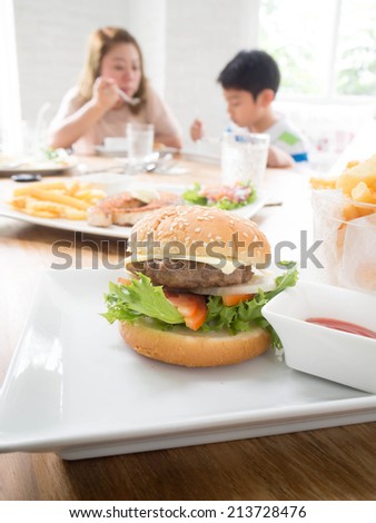 Hamburger on table with mother and son eating blur background