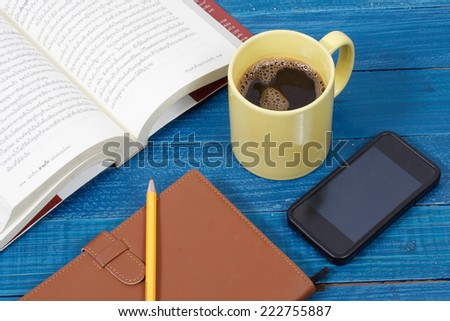 Notebook with smart phone and coffee mug on blue wooden