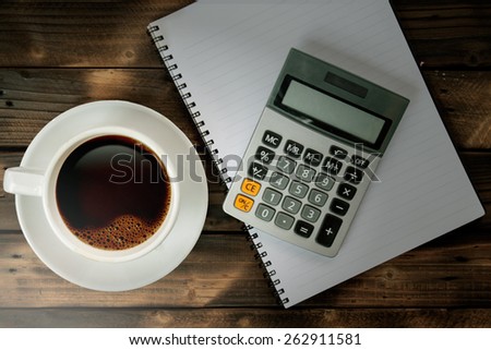 Coffee cup with calculator and notebook on Working desk