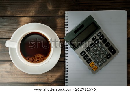 Coffee cup with calculator and notebook on Working desk
