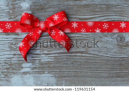 Red christmas ribbon bow on wooden board with copy space