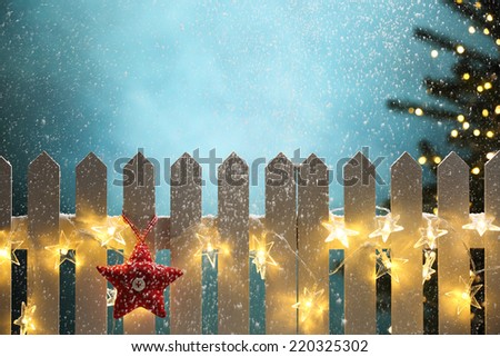 Red fabric star and lights hanging on fence at snowy night,Christmas concept.