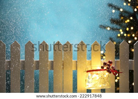 Christmas lights hanging on fence at snowy night