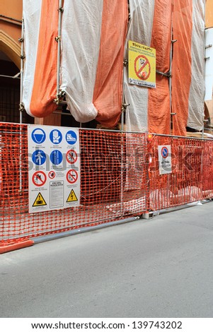 White and orange scaffolding with safety rules poster.