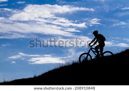 cyclist silhouette in blue sky, clouds, mountain bike