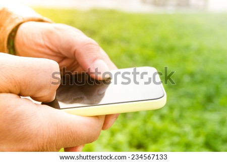 Close-up of male hands using a smart phone, in a park