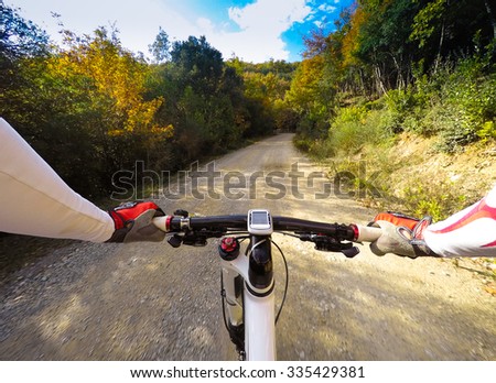 Cyclist on dirty road in a forest. Colors of autumn. POV Original Point of View