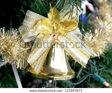 Gold bell ornament with gold ribbon on a Christmas tree